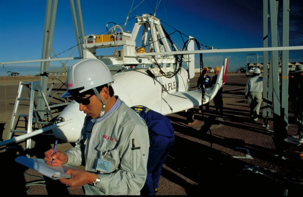 Technicians prepare the HOPE flight experiment vehicle in a test facility.